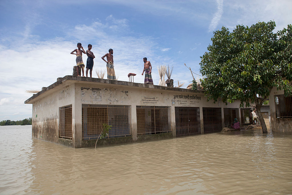 People take shelter on the roof of a school in Jamalpur, Bangladesh in 2016. Around 1.5 million people were affected by flooding that summer, according to the Bangladesh Disaster Management Bureau. In 2020, a third of the country has been hit with dramatic flooding. (Probal Rashid—LightRocket via Getty Images)