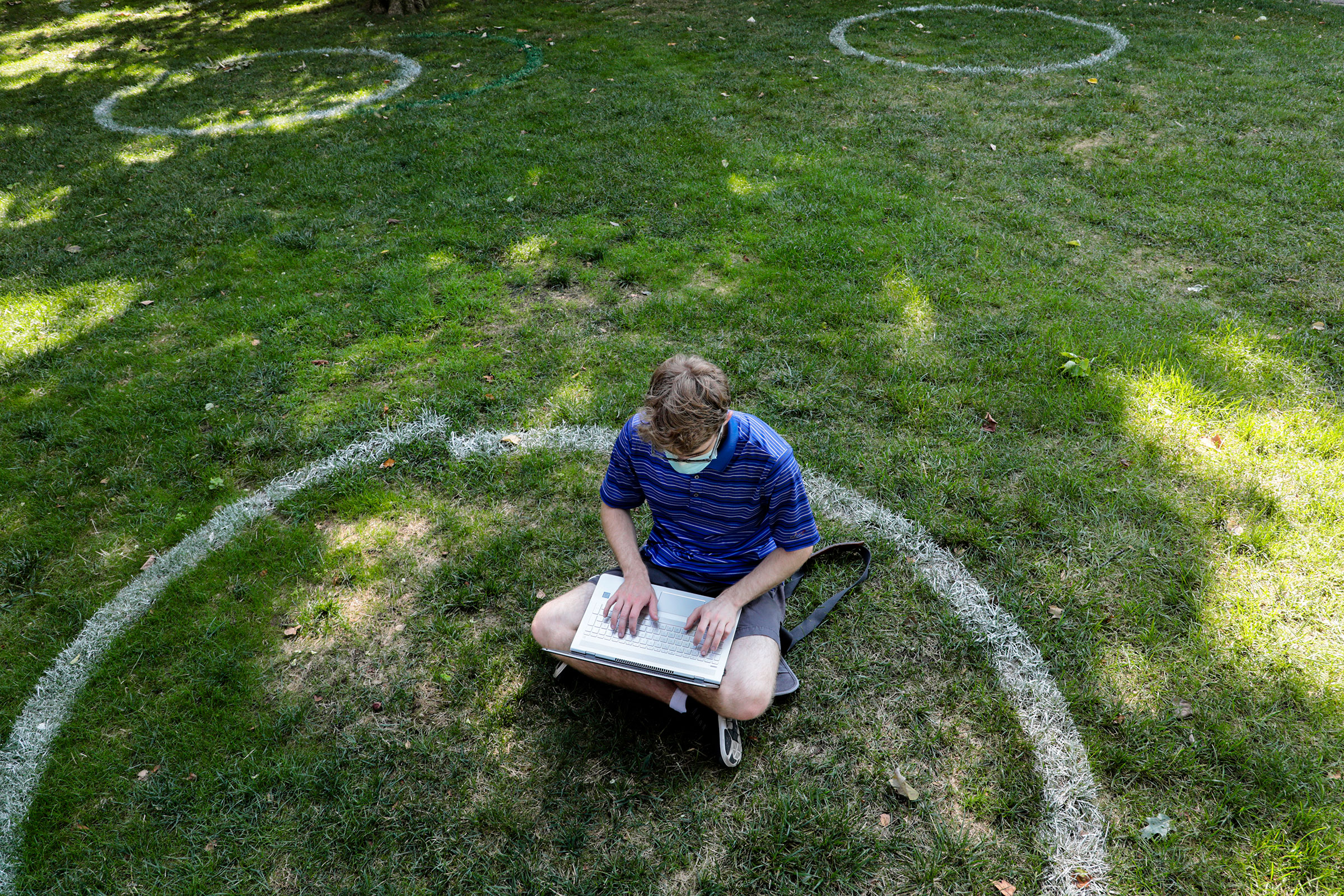 Logan Armstrong, a Cincinnati junior, works while sitting inside a painted circle on the lawn of the Oval during the first day of fall classes on at Ohio State University on Aug. 25, 2020. (Joshua A. Bickel—The Columbus Dispatch/AP)