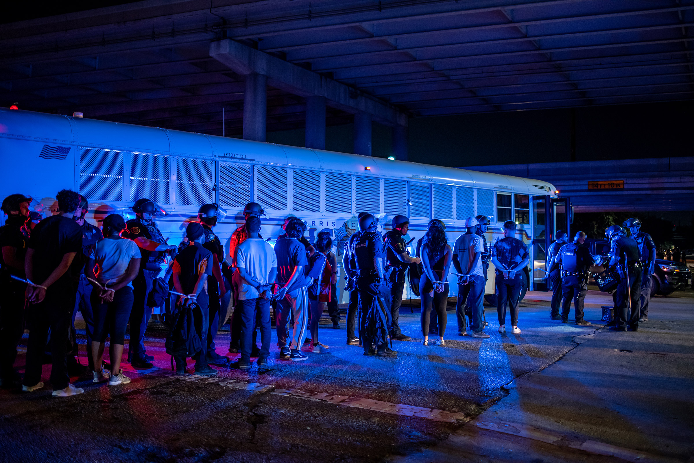 A group of people being placed under arrest stand by a Harris County Jail bus in Houston on June 2, 2020.