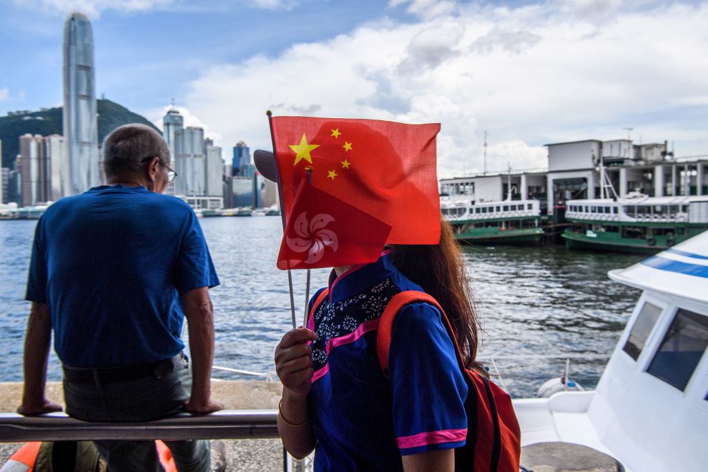A woman holds Chinese and Hong Kong flags as she disembarks from a boat in Victoria Harbour on the 23rd anniversary of the city's handover from Britain in Hong Kong on July 1, 2020. (Anthony WALLACE—AFP/Getty Images)