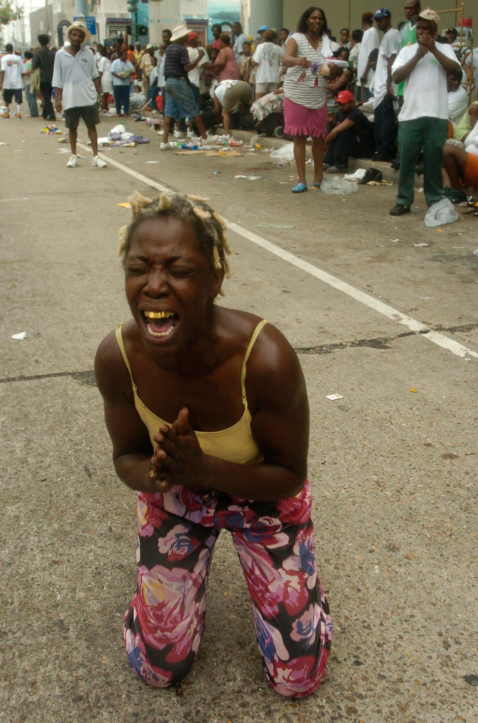 Angela Perkins drops to her knees asking for help among thousands of people gathered at the New Orleans Convention Center waiting in the aftermath of Hurricane Katrina on Sept. 1, 2005