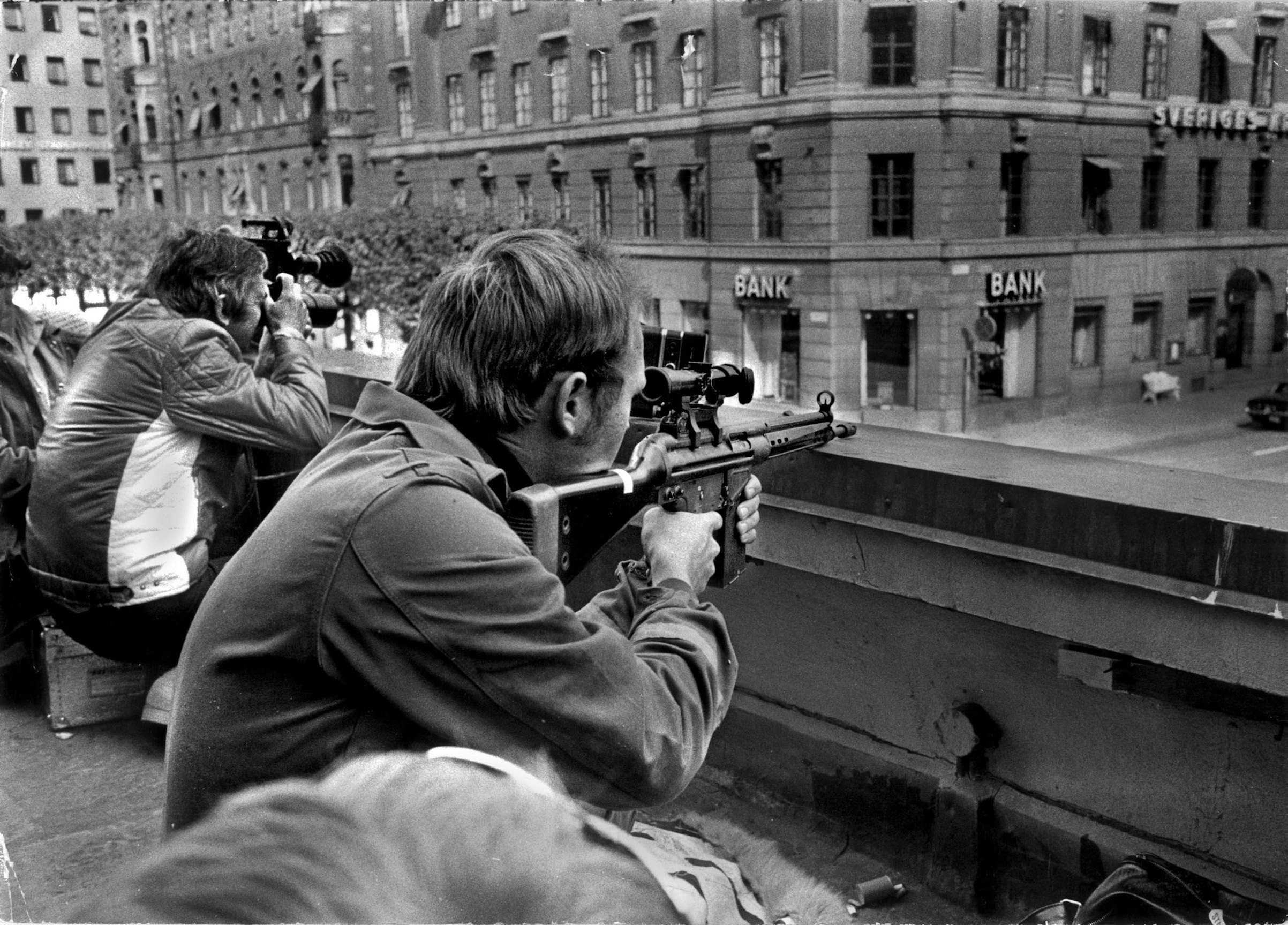 Press photographers and police snipers lie side by side on a roof opposite the Kreditbanken bank on Norrmalmstorg square in Stockholm on Aug. 24, 1973. A misfired robbery turned into a six-day standoff that gave birth to the phrase "Stockholm syndrome." (AFP via Getty Images)