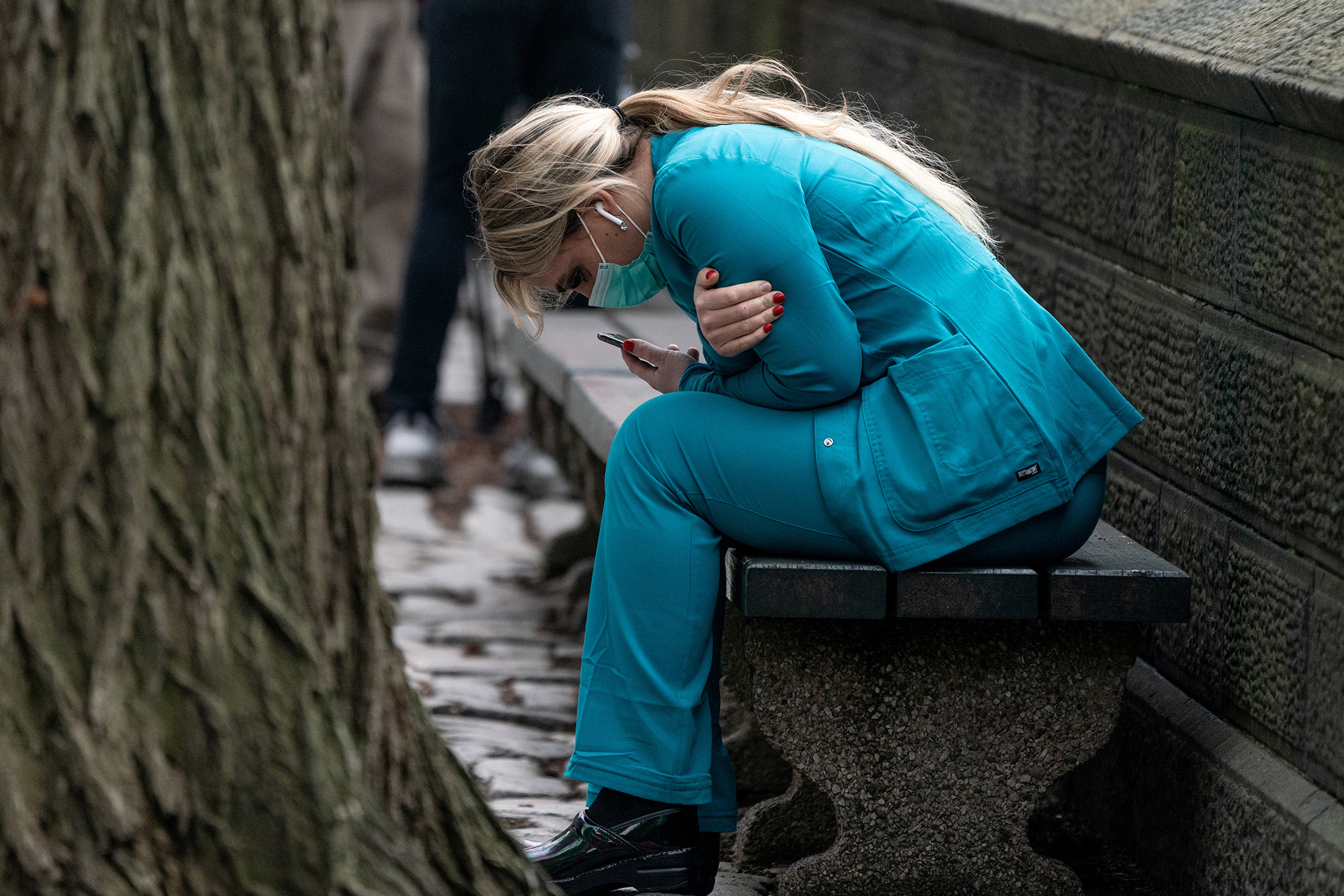 A healthcare worker sits on a bench near Central Park in New York City, on Mar. 30, 2020. (Jeenah Moon–REUTERS)
