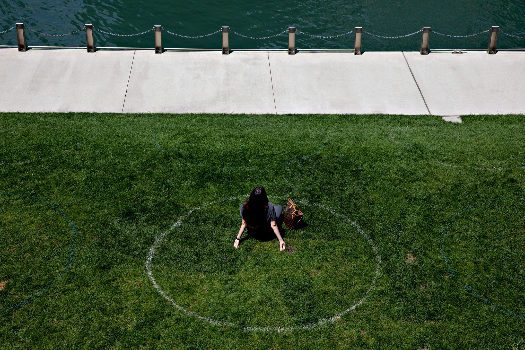 A woman sits in a social distance circle along the Chicago River in Chicago, on Aug. 4, 2020. (Daniel Acker/The New York Times–Redux)