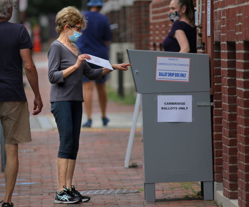A voter drops off a mail-in ballot in a collection box in Cambridge, Mass. on Aug. 25.