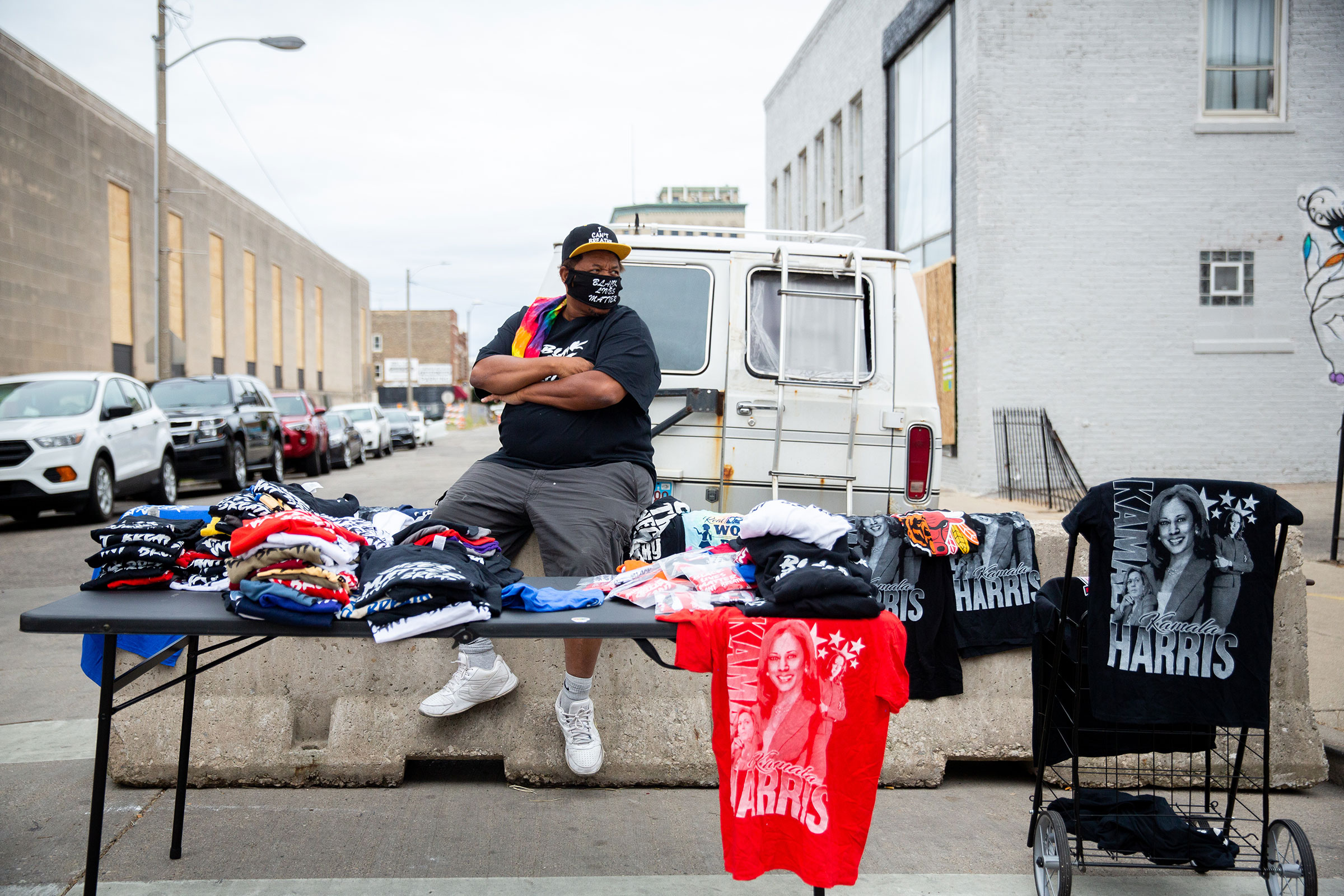 A street vendor selling T-shirts observes a crowd of protesters marching near the county courthouse in Kenosha, Wis., on Sept. 1, 2020. (Patience Zalanga for TIME)