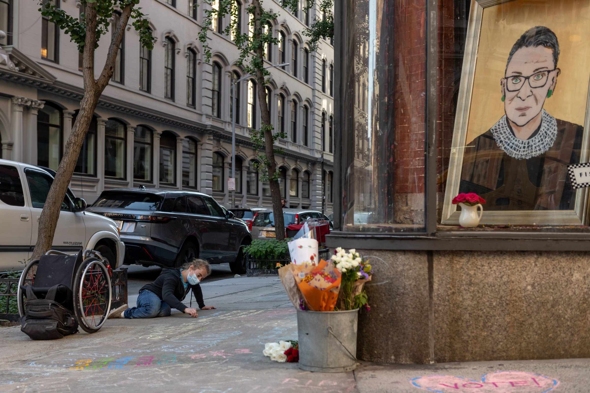 A woman wearing a mask writes a message in chalk in front of a painting of the late Associate Justice of the Supreme Court Ruth Bader Ginsburg on Sept. 19 in New York City. Ginsburg died on Sept. 18.