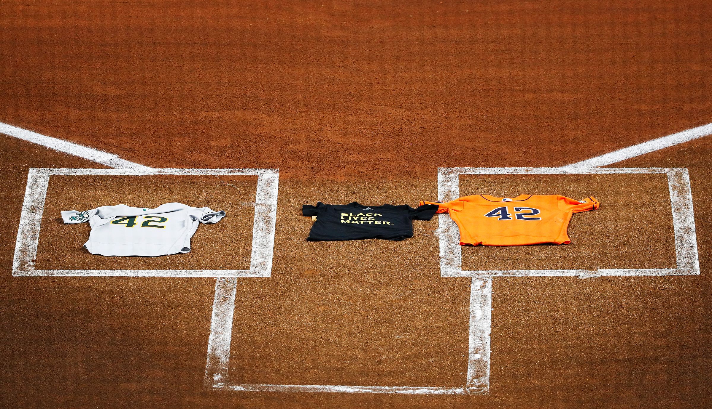 An Oakland Athletics jersey, laid by Marcus Semien, and a Houston Astros jersey, laid by Martin Maldonado, both bearing the No. 42 in honor of Jackie Robinson, flank a Black Lives Matter T-shirt covering home plate in Houston on Aug. 28 (Kevin M. Cox—The Galveston County Daily News/AP)