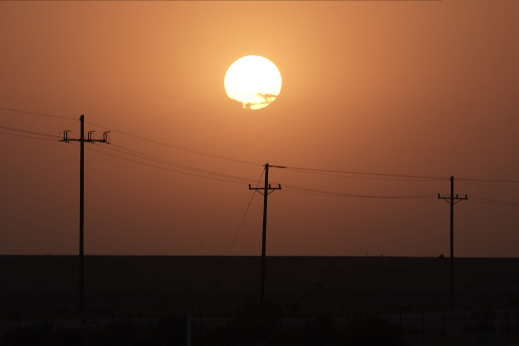 The sun rises over power lines near Imperial, California, on Tuesday, Aug. 18, 2020. California is bracing for another round of rolling blackouts Tuesday as unrelenting heat drives electricity demand to an all-time high, straining a power grid thats already been pushed to the brink of failure. (Bing Guan–Bloomberg/Getty Images)