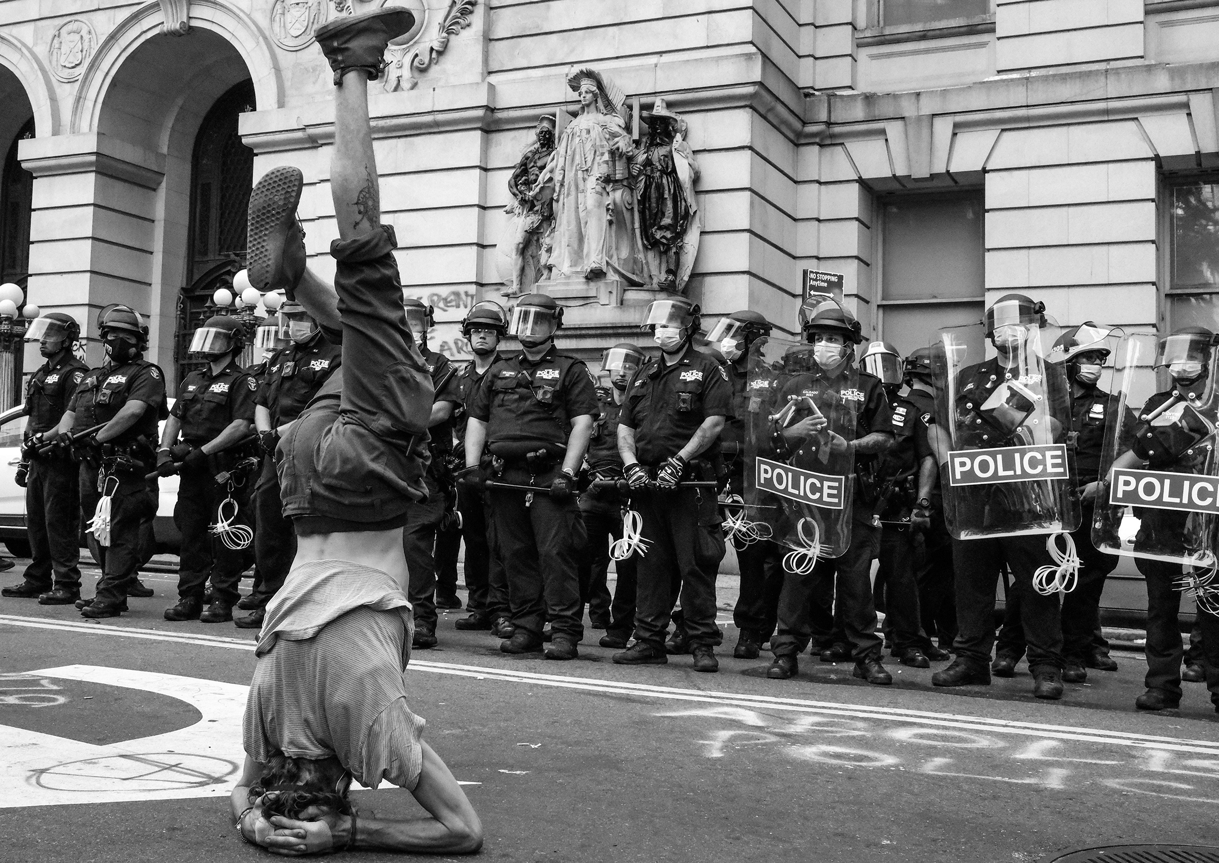 A protester stands on his head in front of a line of NYPD near City Hall during the first attempt to take over the so-called "Abolition Park," a makeshift camp in City Hall Park made up of people protesting police brutality. (Clay Benskin)