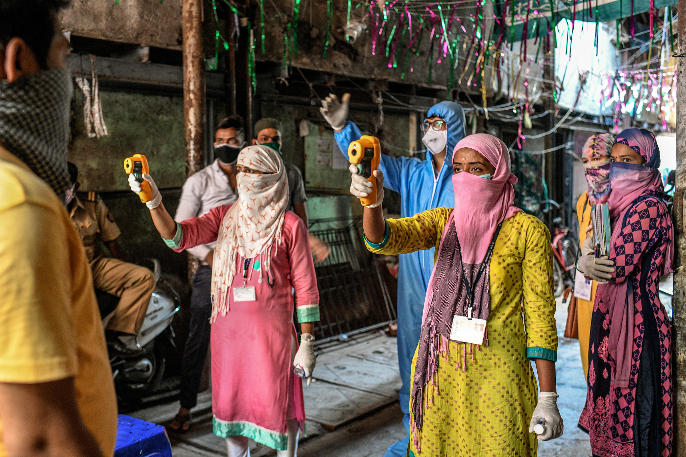 Health workers check residents' temperatures during a mass screening for COVID-19 symptoms in Dharavi in April. (Atul Loke—Panos Pictures/Redux)