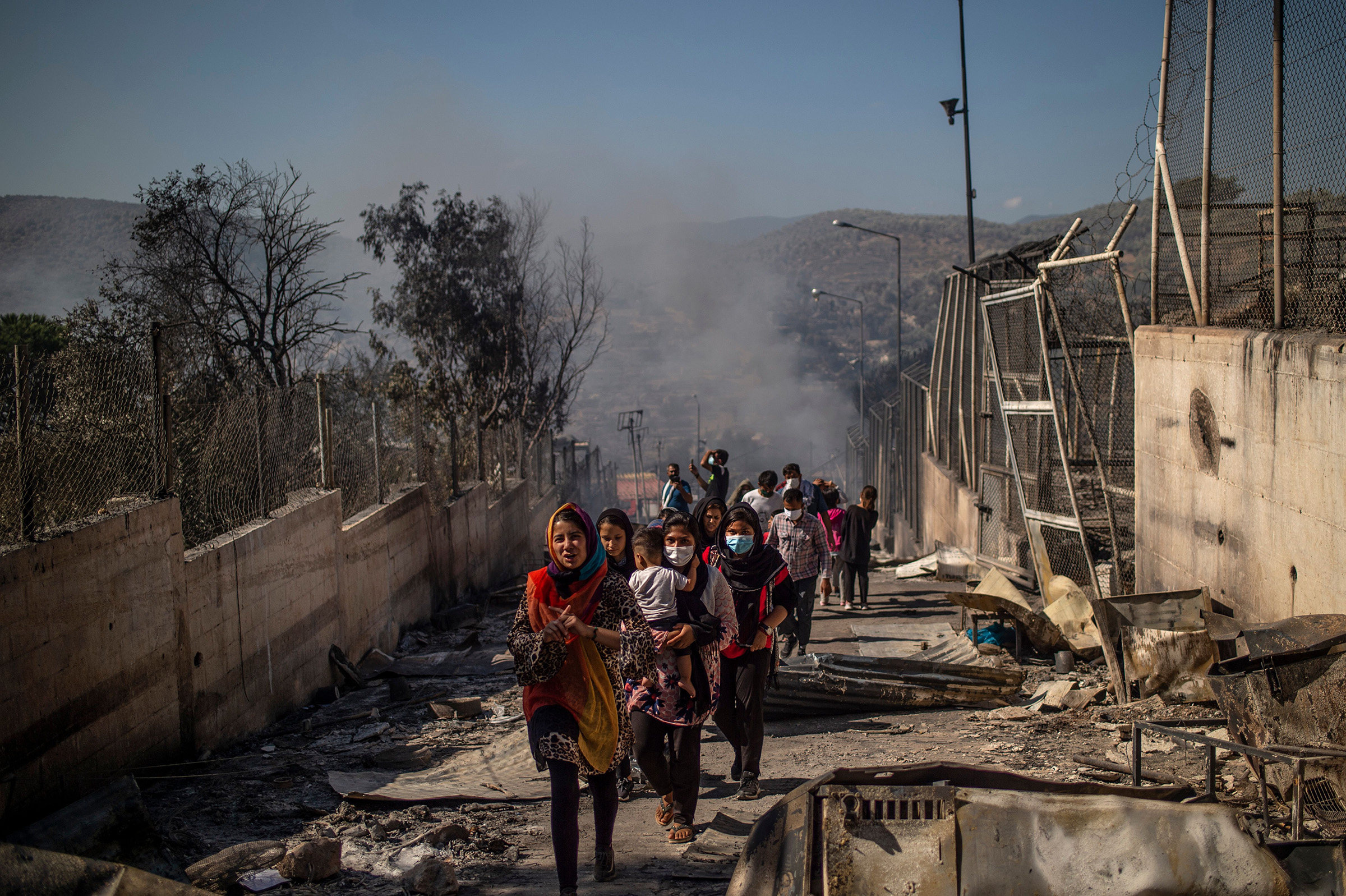 People walk in the burnt camp of Moria on the island of Lesbos after a major fire broke out, on Sept. 9, 2020. (Angelos Tzortzinis—AFP/Getty Images)