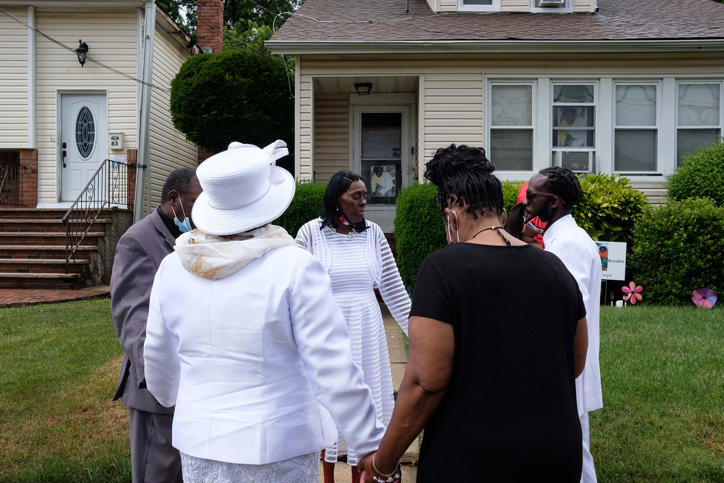 Family members stop to pray in front of his house during a procession from the church to Greenfield Cemetery in Hempstead, N.Y.