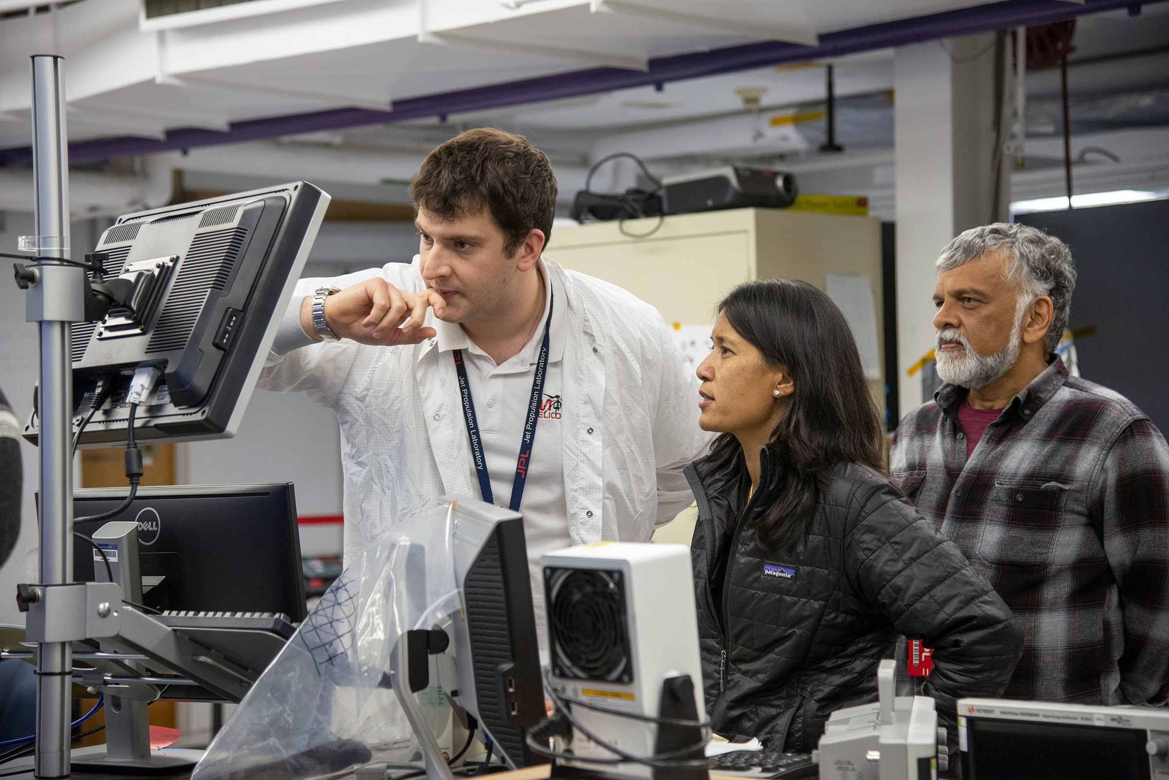 In an undated photo from JPL-Caltech/NASA, from left, Teddy Tzanetos, a roboticist at the NASA Jet Propulsion Laboratory; MiMi Aung, the Mars Helicopter's project manager; and Bob Balaram, its chief engineer; observe a test flight at NASA's Jet Propulsion