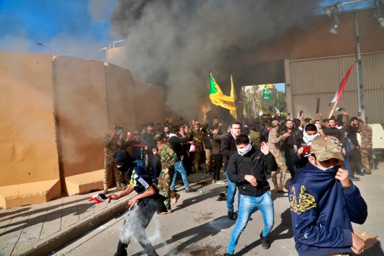 Protesters run from tear gas at the U.S. embassy compound in Baghdad, Dec. 31, 2019.