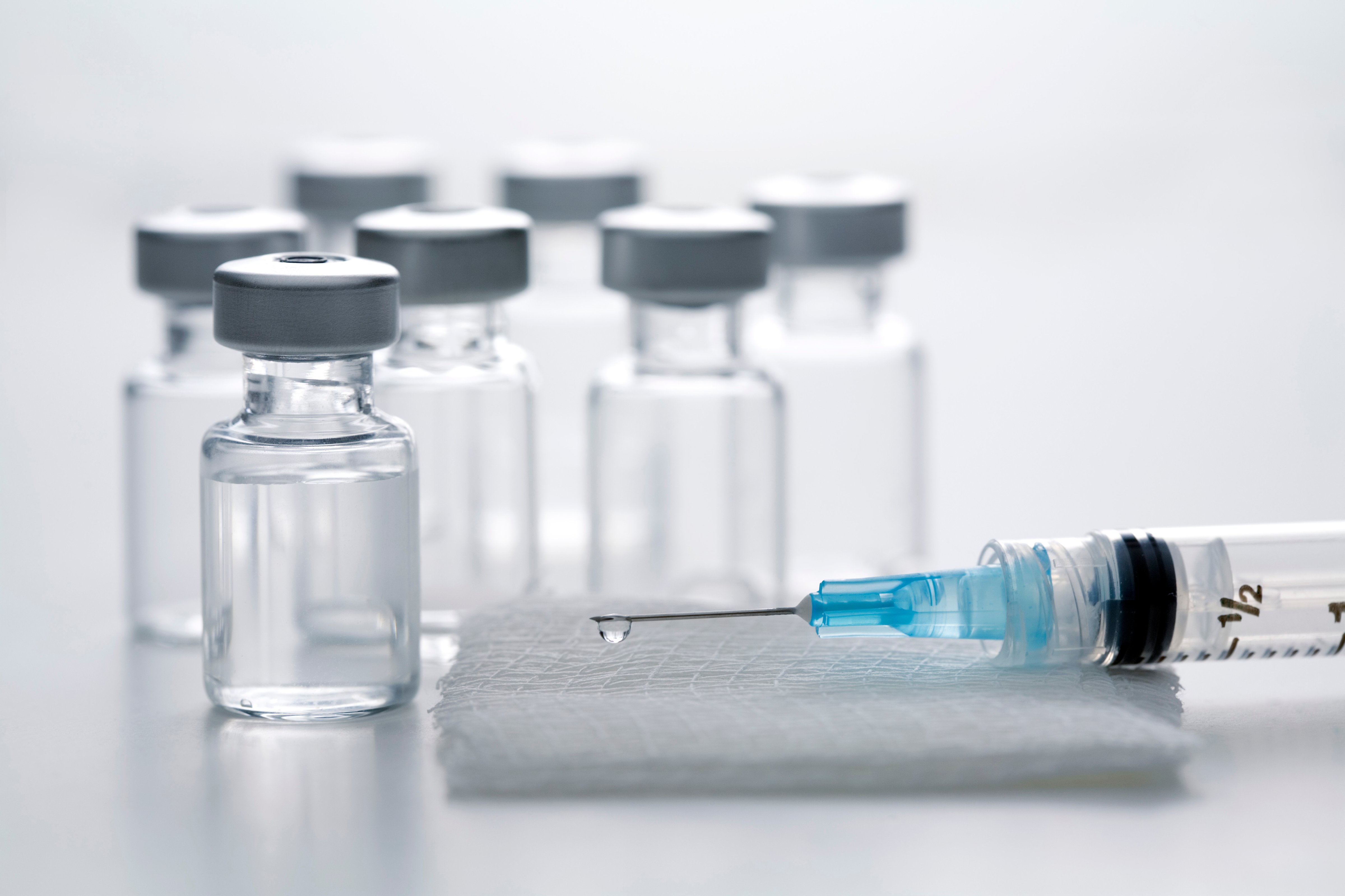 Syringe on gauze pad with vaccine bottles