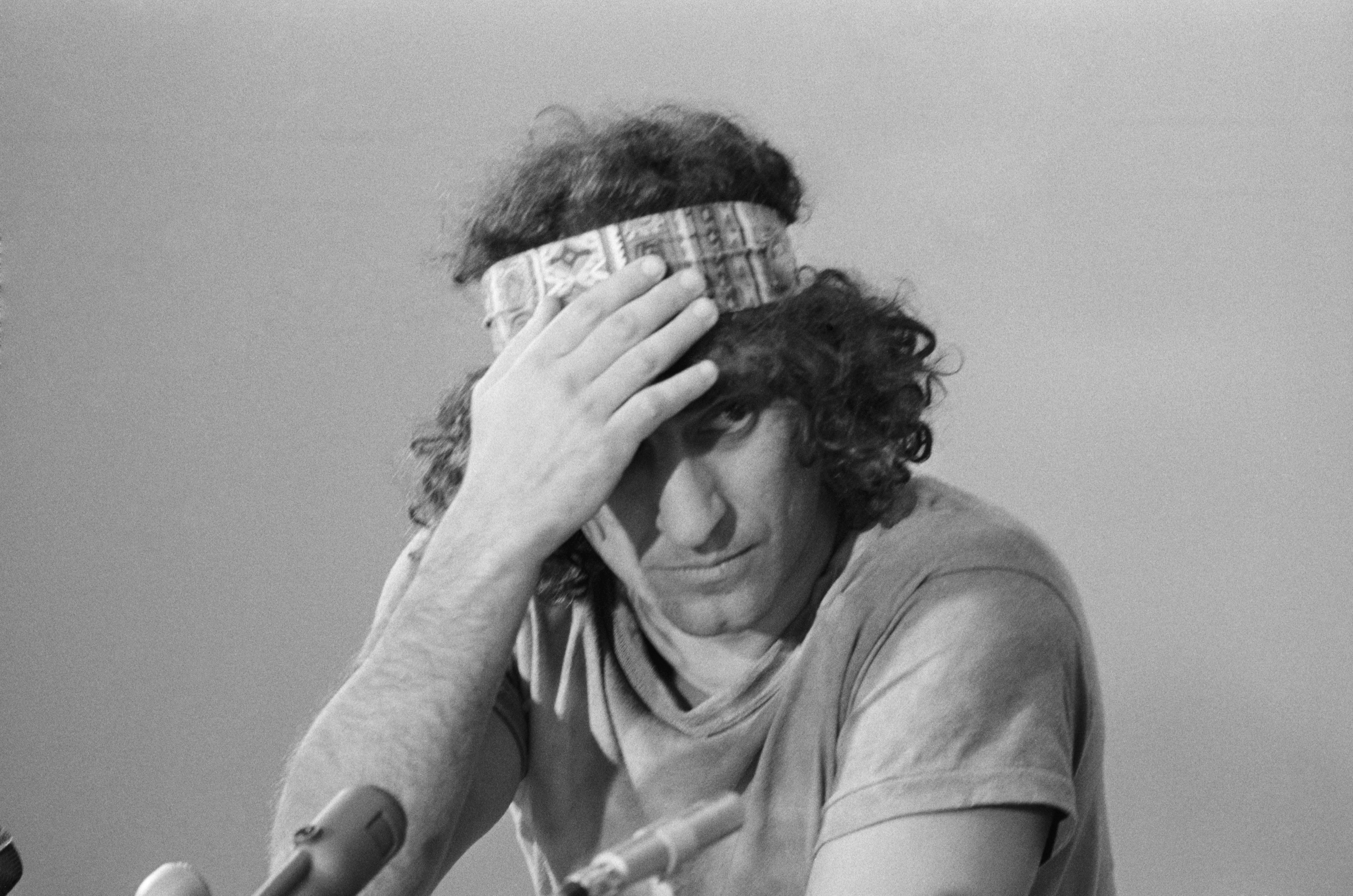 Abbie Hoffman adjusts his headband during a news conference about the trial (Bettmann Archive)