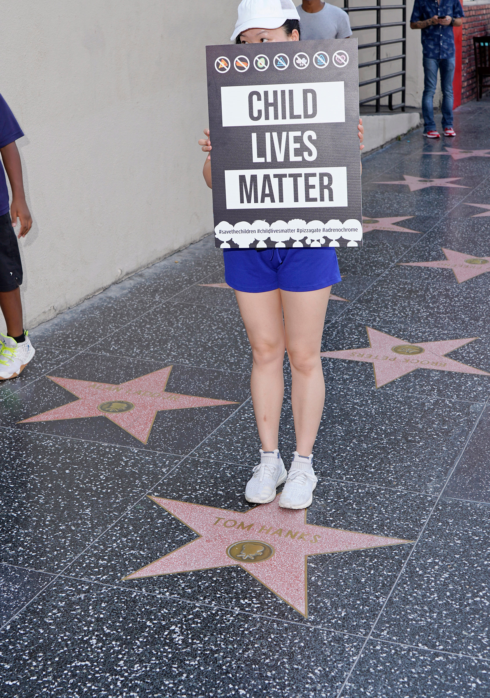 A protester stands on Tom Hanks' star on the Hollywood Walk of Fame, Aug. 22, 2020.