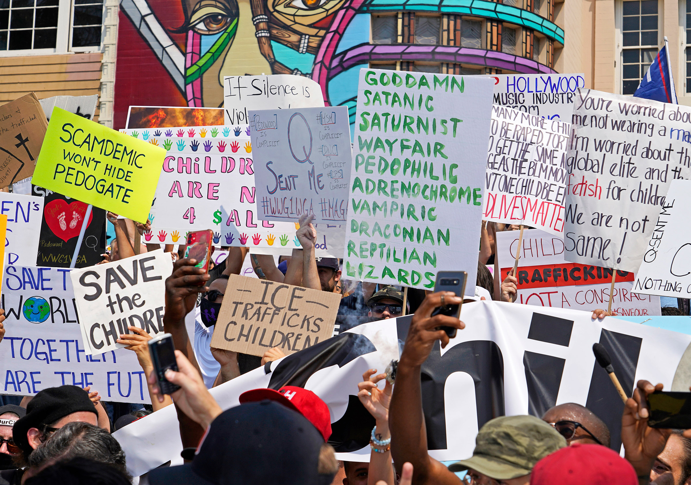 Signs showing various conspiracy theories at a Save Our Children rally in Los Angeles, Aug. 22, 2020. (Jamie Lee Curtis Taete)