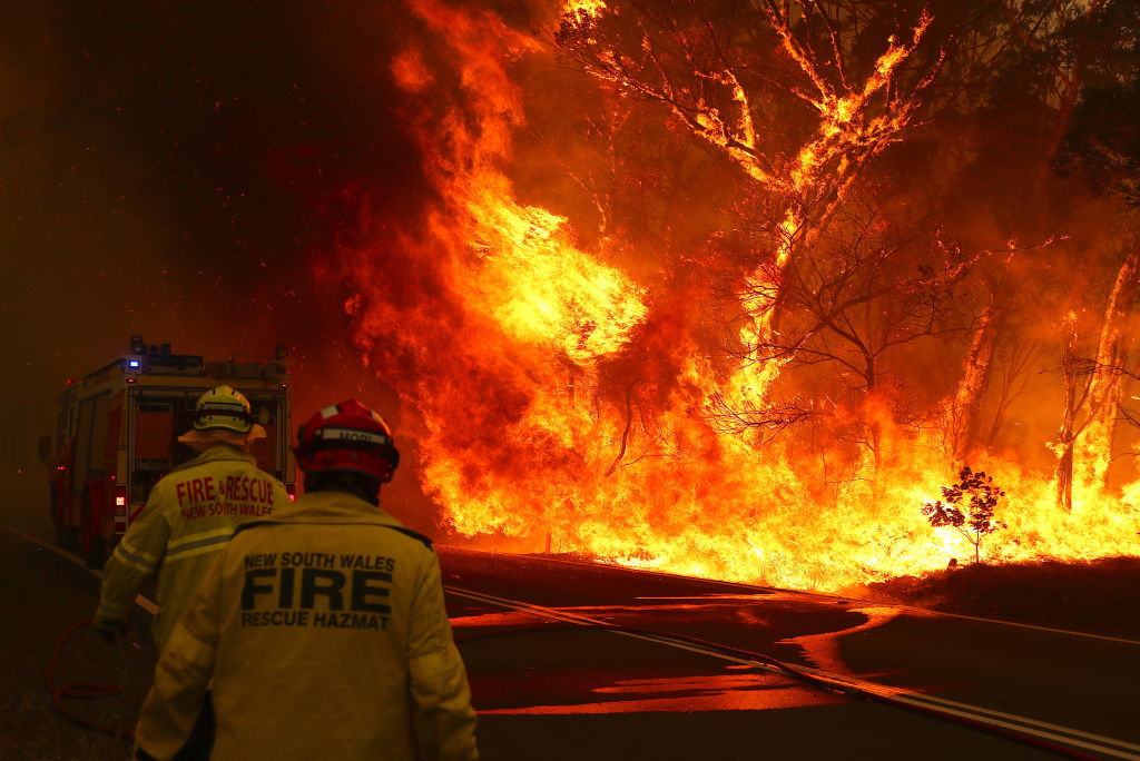 Fire and Rescue personnel run to move their truck as a bushfire burns next to a major road and homes on the outskirts of the town of Bilpin in Sydney, Australia on Dec. 19, 2019. (David Gray—2019 Getty Images)