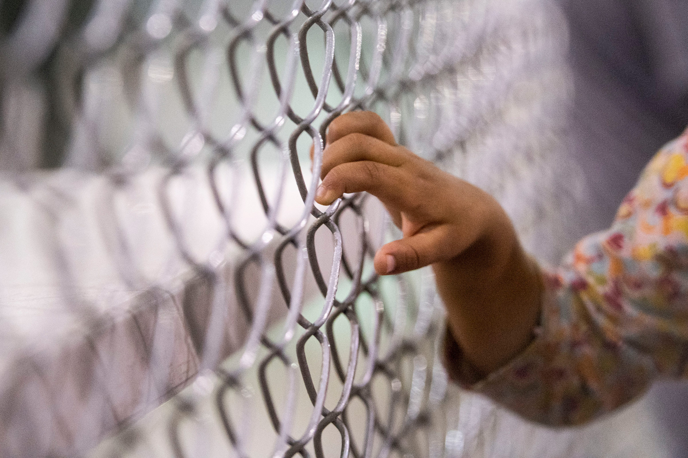 A child holds onto a fence in the U.S. Border Patrol Central Processing Center in McAllen, Texas, on Aug. 12, 2019. (Carolyn Van Houten—The Washington Post/Getty Images)