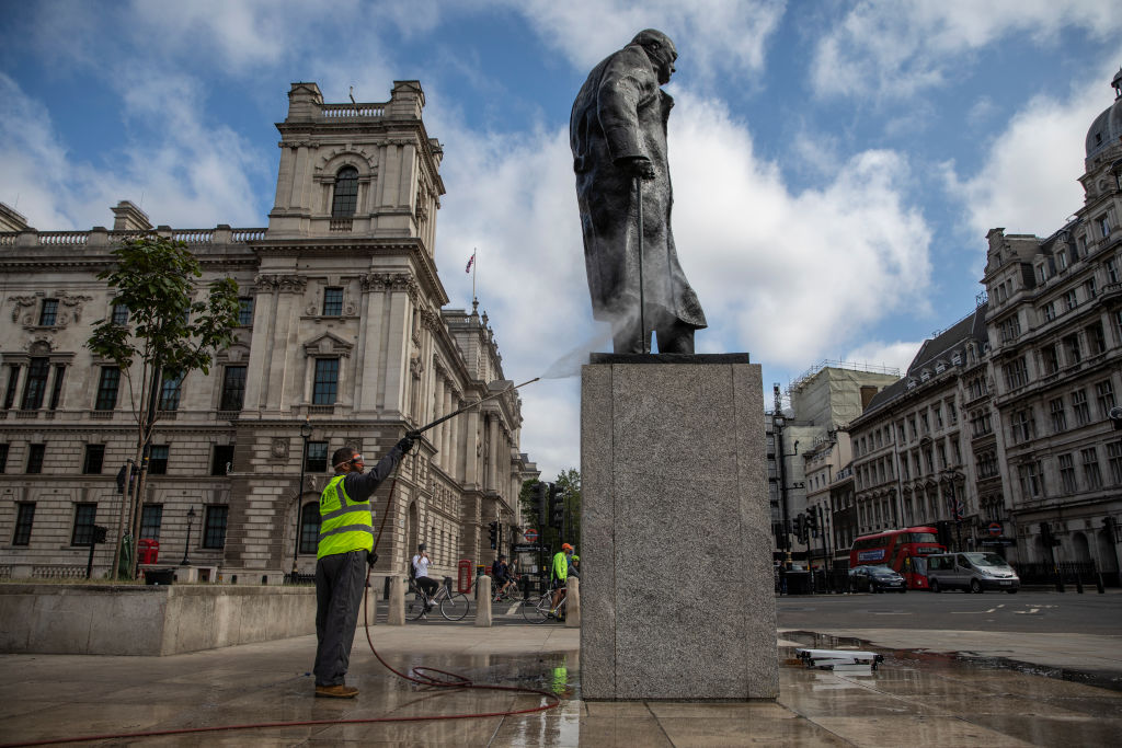 A worker cleans the Churchill statue in Parliament Square that had been spray painted with the words 'was a racist' on June 8, 2020 in London. (Dan Kitwood—Getty Images)