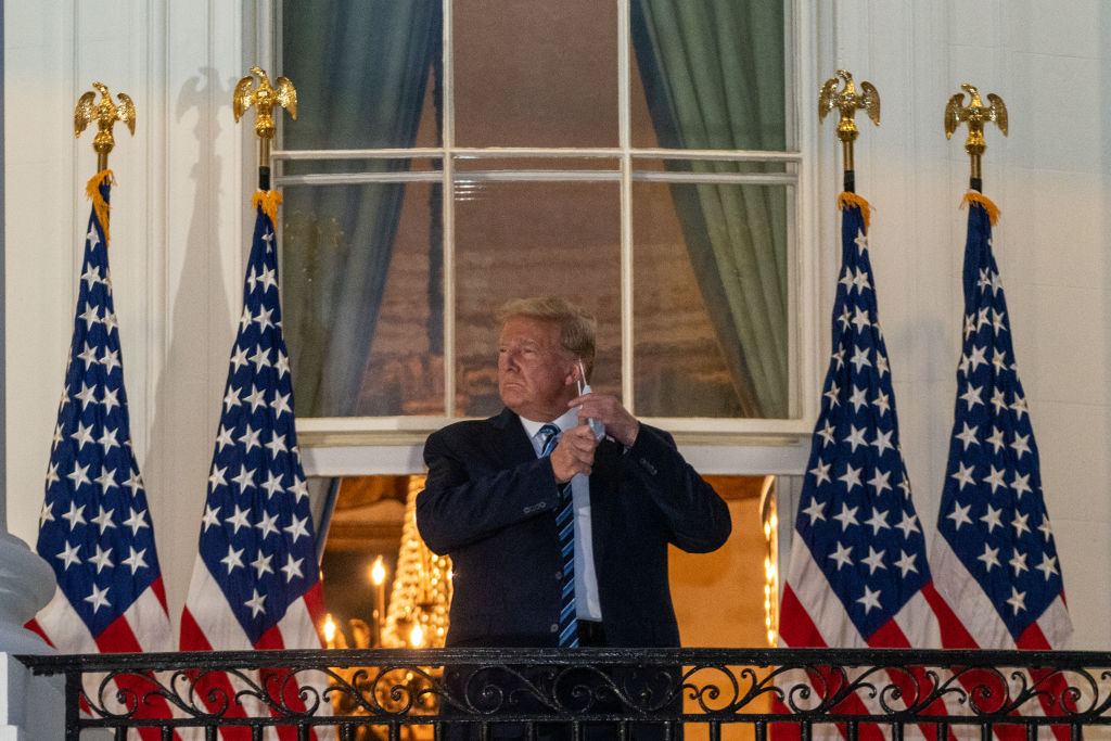 U.S. President Donald Trump removes his protective mask on the Truman Balcony of the White House in Washington, D.C., U.S., on Monday, Oct. 5, 2020. (Ken Cedeno—Polaris/Bloomberg via Getty Images)