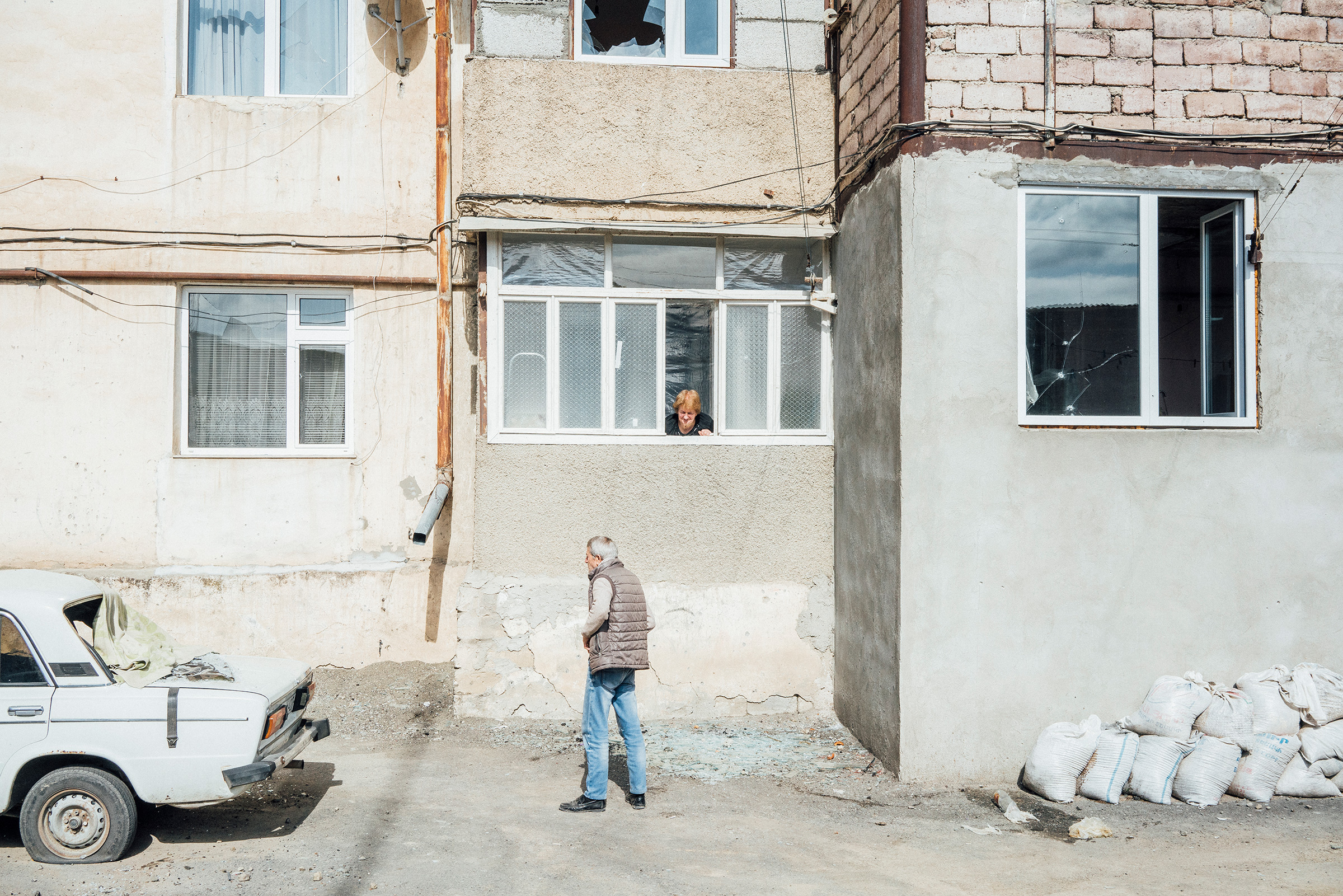 A woman speaks with a man through an open window of a shelled building in Stepanakert.