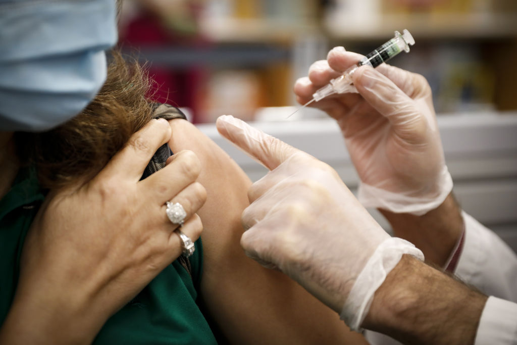 A pharmacist administers a free flu shot vaccine to a customer.