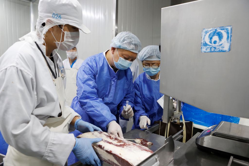 Medical workers wearing protective suits collect samples from imported frozen beef for COVID-19 tests at a food factory in Shanghai, China on August 18, 2020. (Yin Liqin&mdash;China News Service/Getty Images)