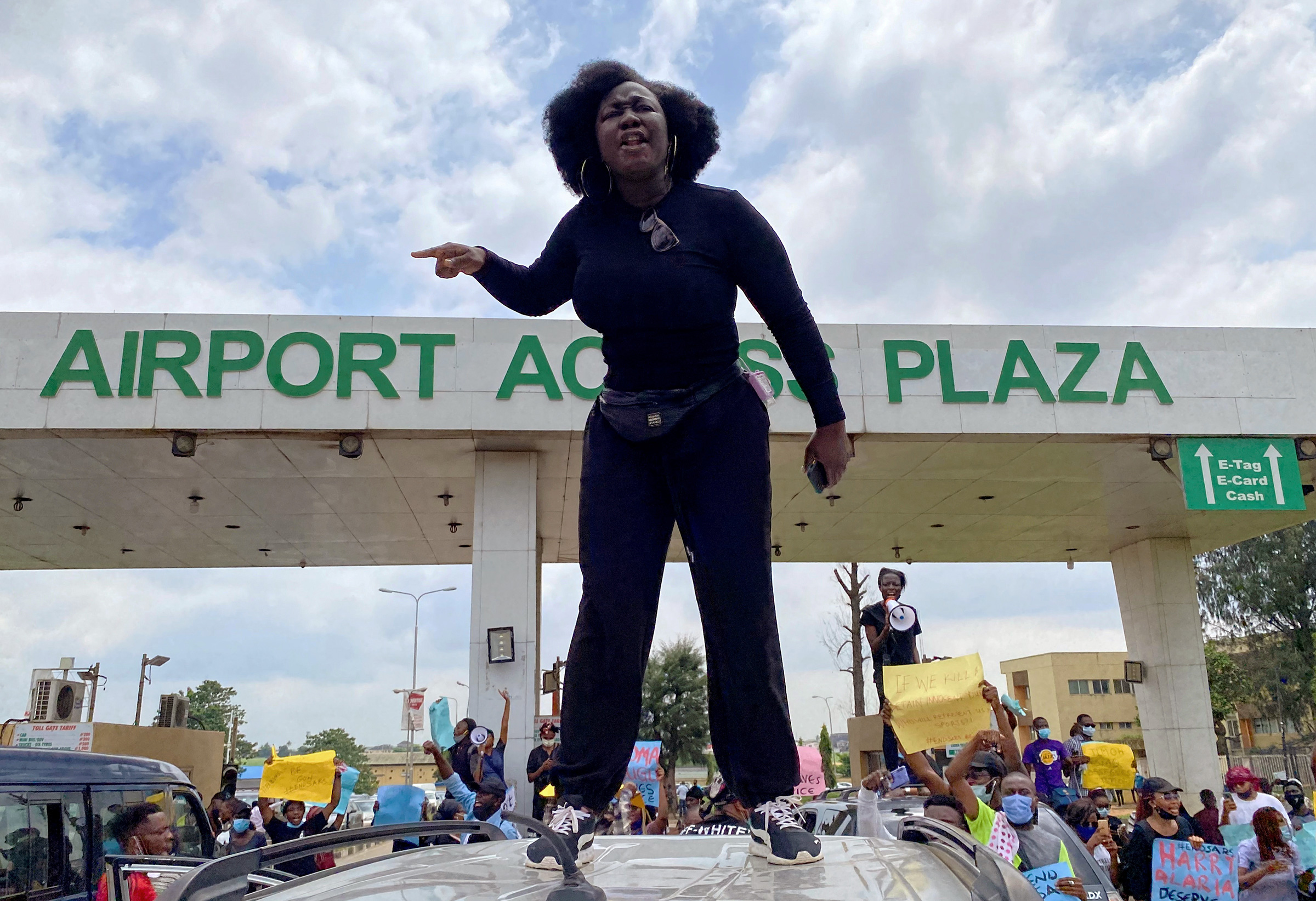 A demonstrator stands atop a vehicle and shouts slogans as others carry banners while blocking a road leading to the airport in Lagos on Oct. 12, 2020. (Seun Sanni—Reuters)