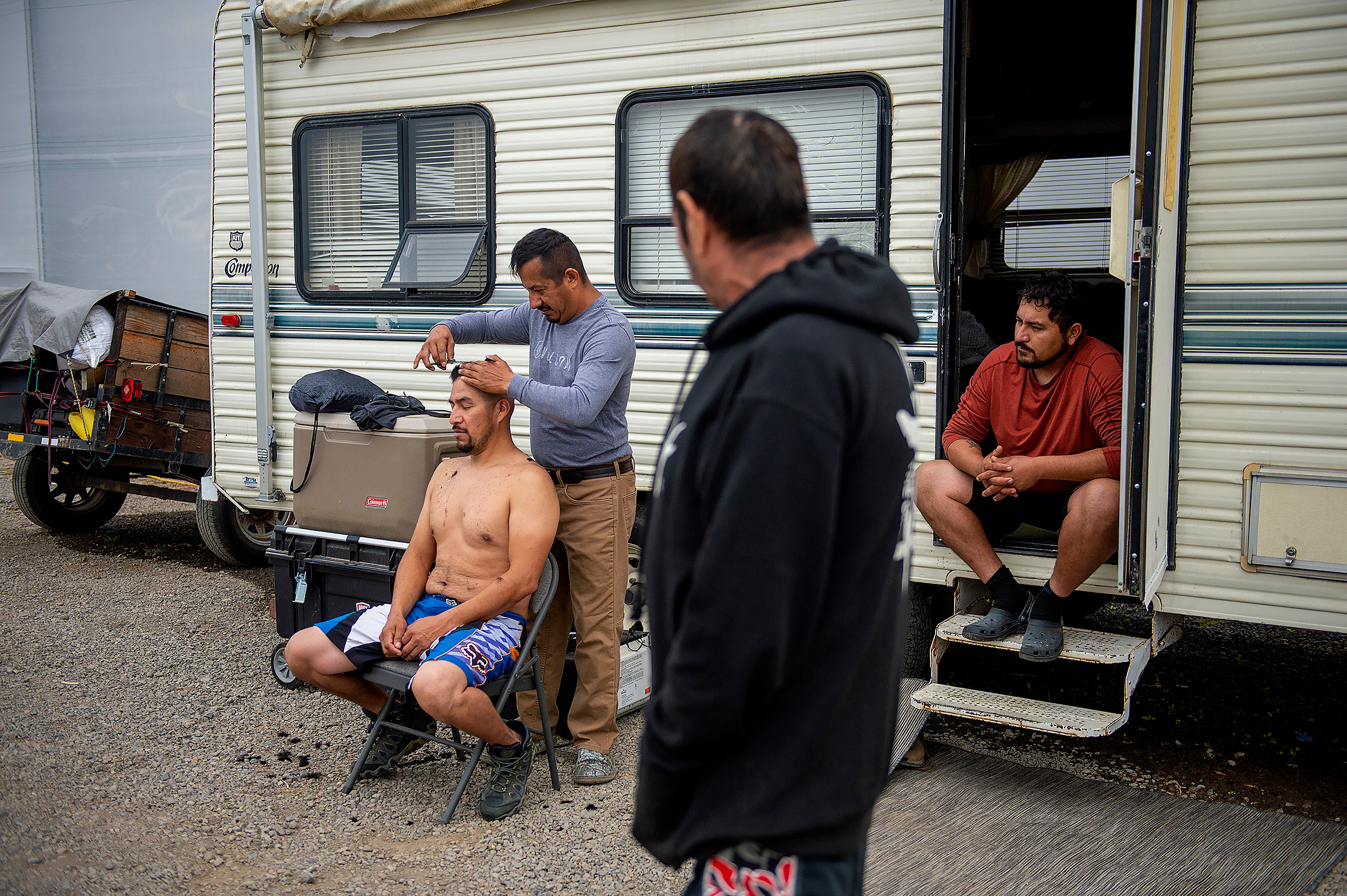 Julio Hernandez cuts the hair of his brother, Alvaro Hernandez, at a farm that opened space to people displaced by wildfires in Central Point, Ore., on Sept. 26, 2020. The Almeda Fire leveled some of the only affordable housing for the immigrants who work the fields, kitchens and construction sites of southern Oregon.