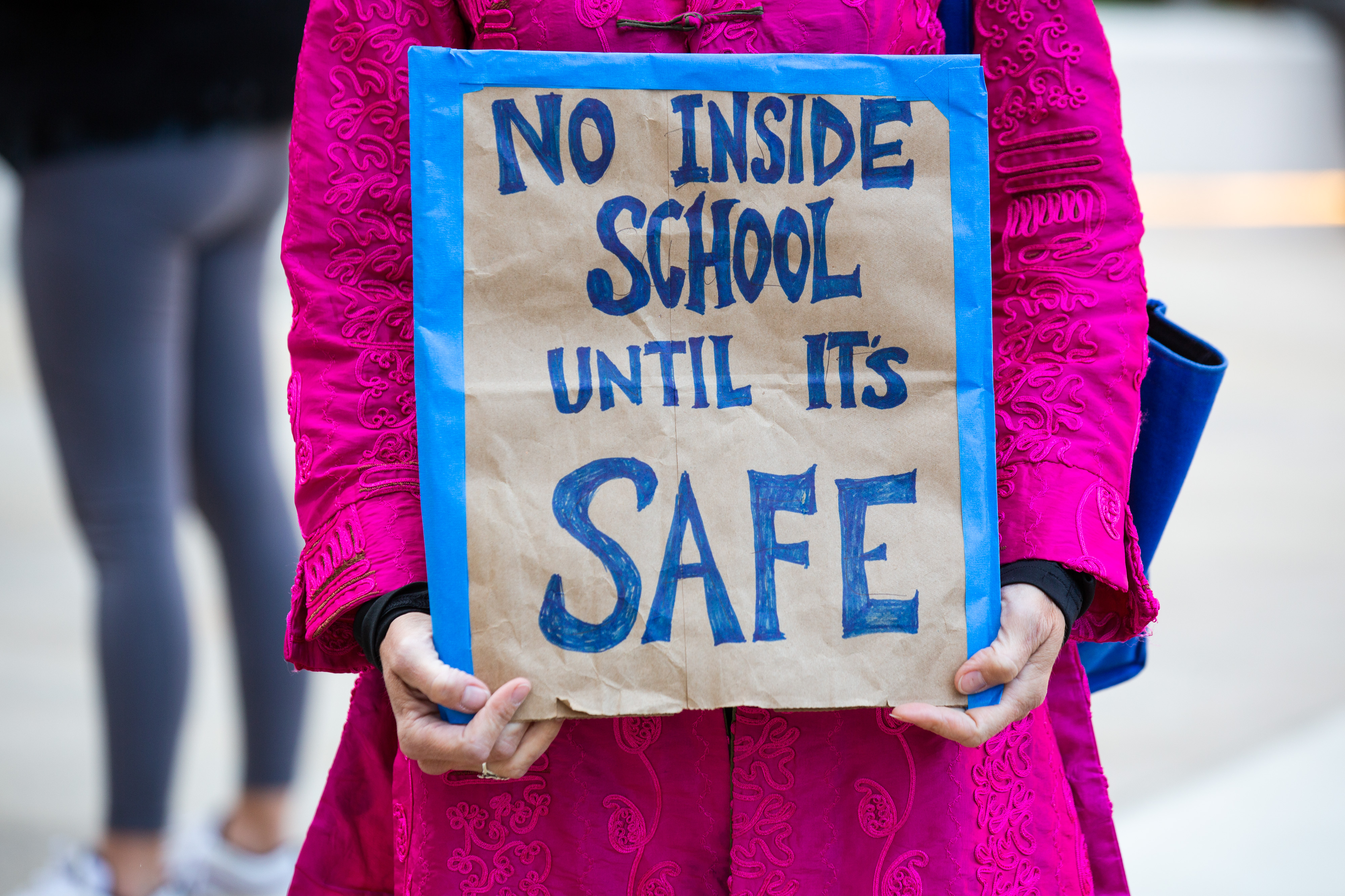 A parent holds a sign reading No inside school until it's safe during a protest outside Murry Bergtraum High School in New York City on Sept. 21, 2020.