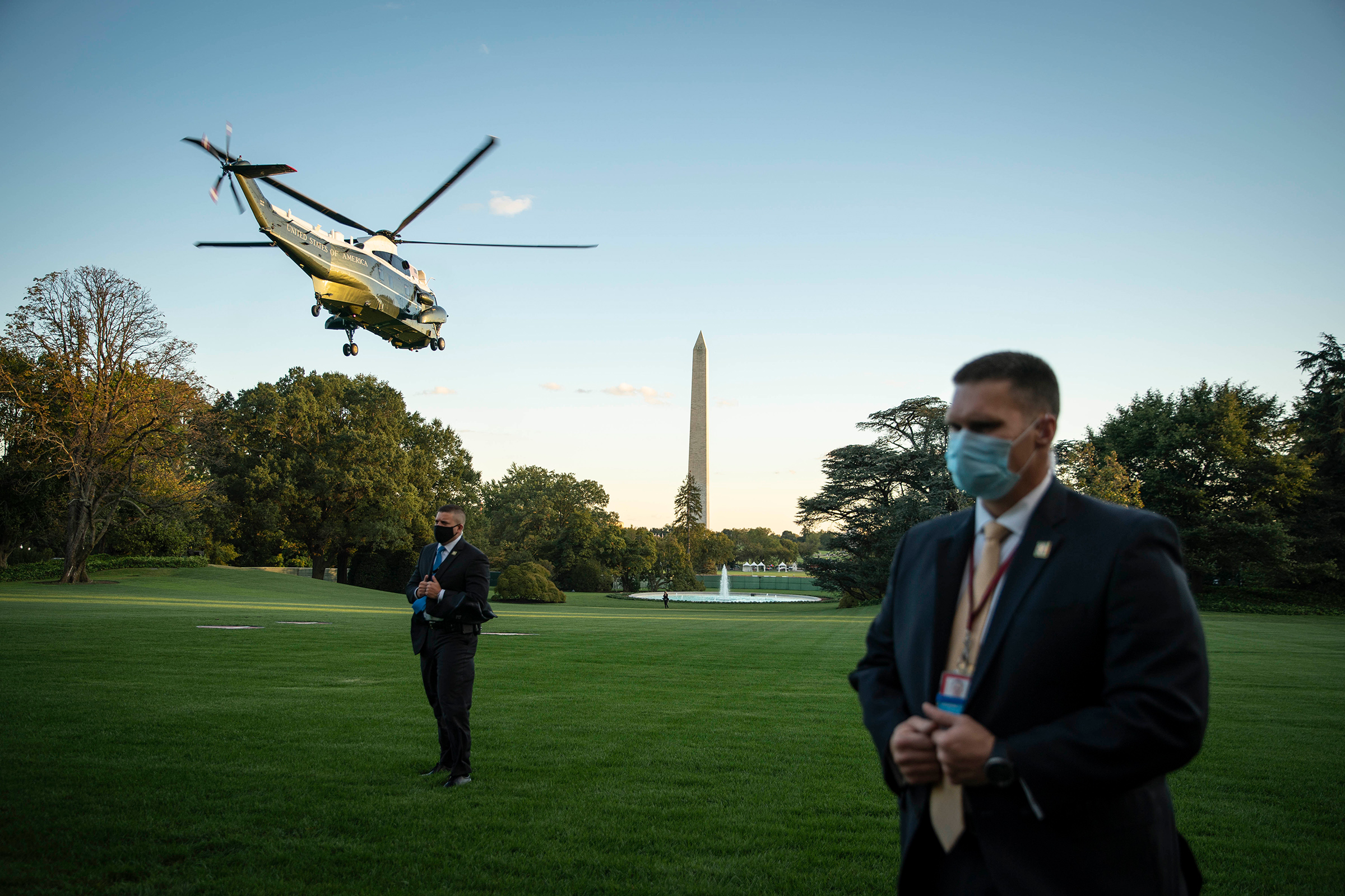 Secret Service agents wearing protective face masks stand by as Marine One, carrying President Trump, departs from the South Lawn of the White House on Oct. 2, 2020.