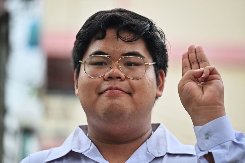 Pro-democracy activist Bunkueanun "Francis" Paothong flashes the three-finger salute before entering the Dusit Police Station to answer charges of harming Thailand's queen on Oct. 16, 2020. (Lillian SUWANRUMPHA—AFP/Getty Images)