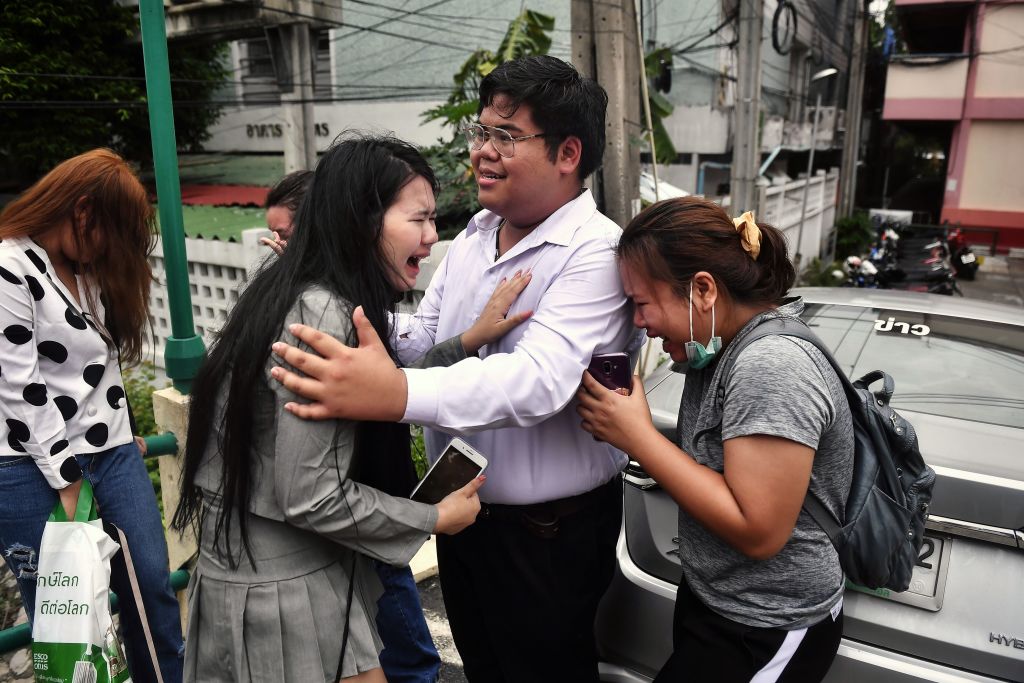 Activist Bunkueanun "Francis" Paothong (C) comforts loved ones before he enters the Dusit Police Station to answer charges of harming Thailand's Queen Suthida in Bangkok on Oct. 16, 2020. (Lillian SUWANRUMPHA—AFP/Getty Images)