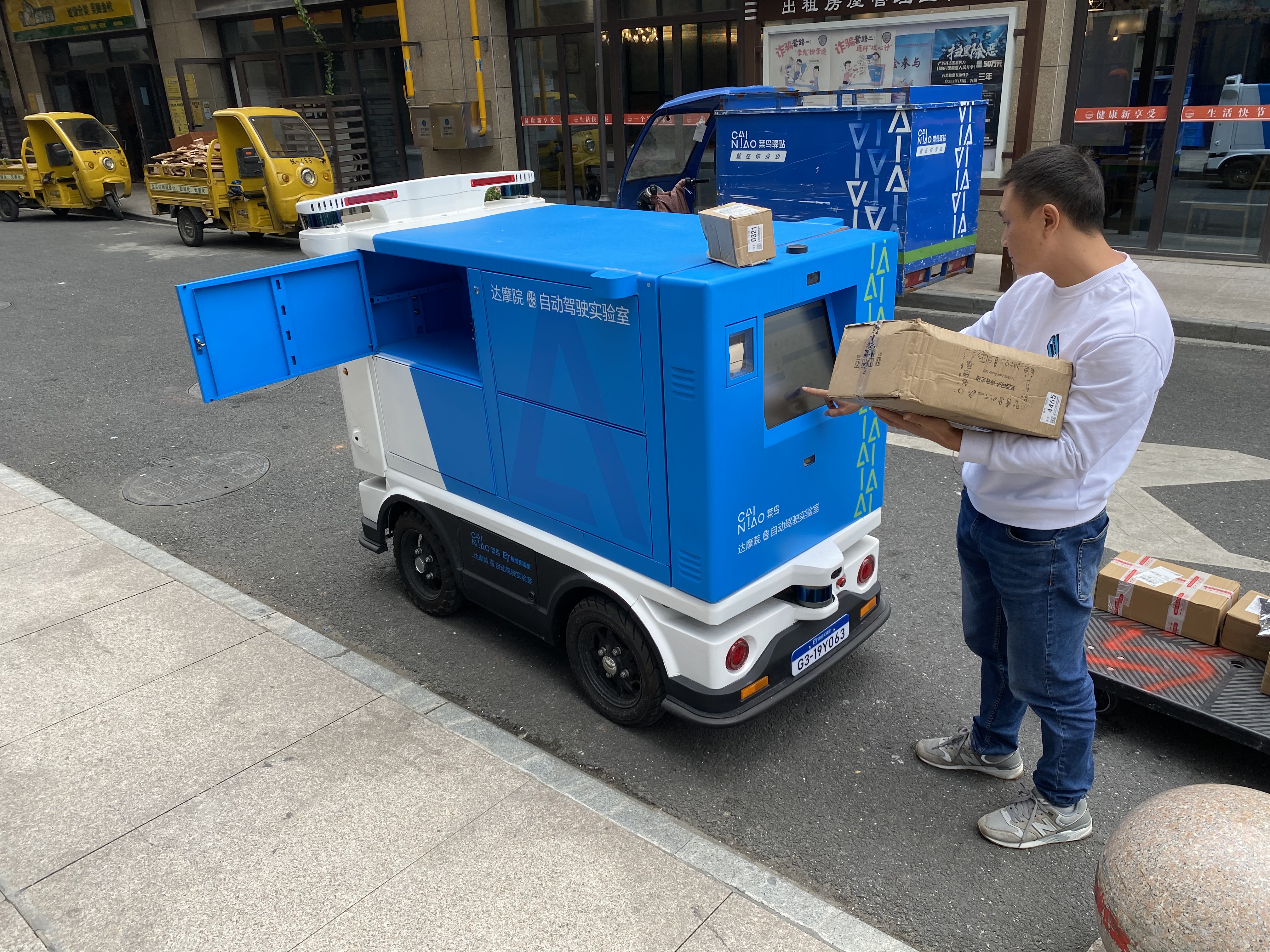 Cainiao engineer Long Fei loads packages onto the firm’s Xiao G automated delivery vehicle in Hangzhou, China on Oct. 19, 2020. (Charlie Campbell)