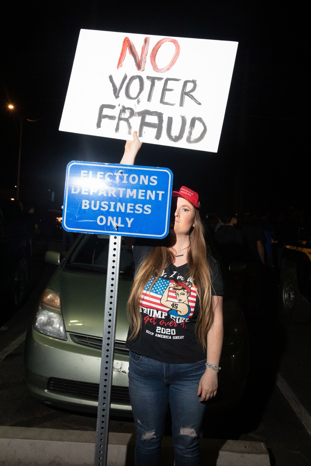 Trump supporter with a sign that reads No Voter Fraud stands by a sign that reads Elections Department Business Only at the Mariscopa County Elections Office in Phoenix, AZ on November 4, 2020