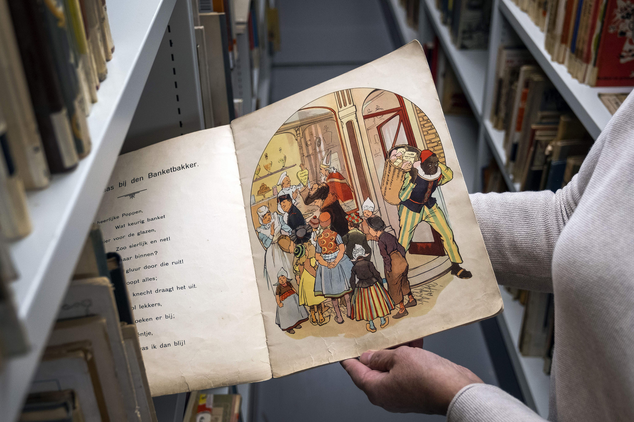 An Amsterdam Public Library employee with a book about Sinterklaas and Zwarte Piet (Black Pete) in Amsterdam, on Nov. 12, 2020. (Ramon Van Flymen—ANP/AFP/Getty Images)