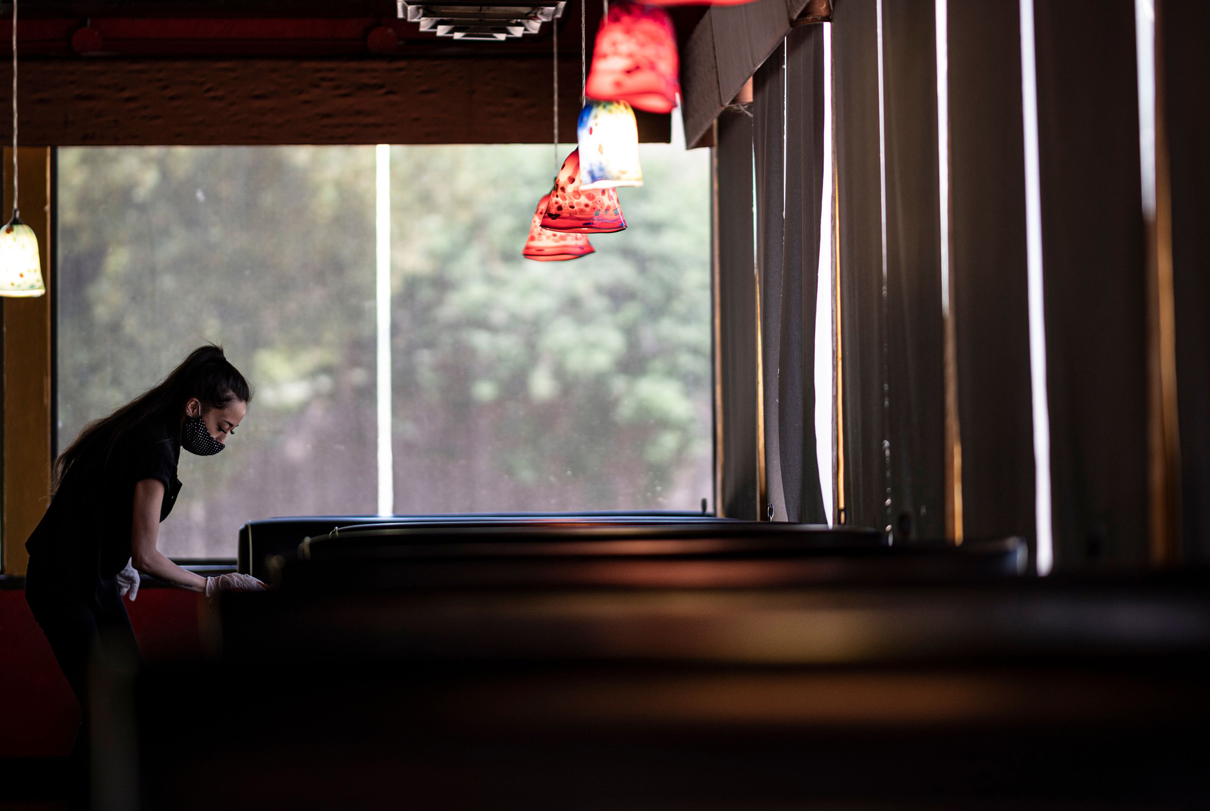 A waitress wearing a mask and gloves disinfects a table in a Restaurant on May 5, 2020 in Stillwater, Oklahoma. (Johannes Eisele—AFP/Getty Images)