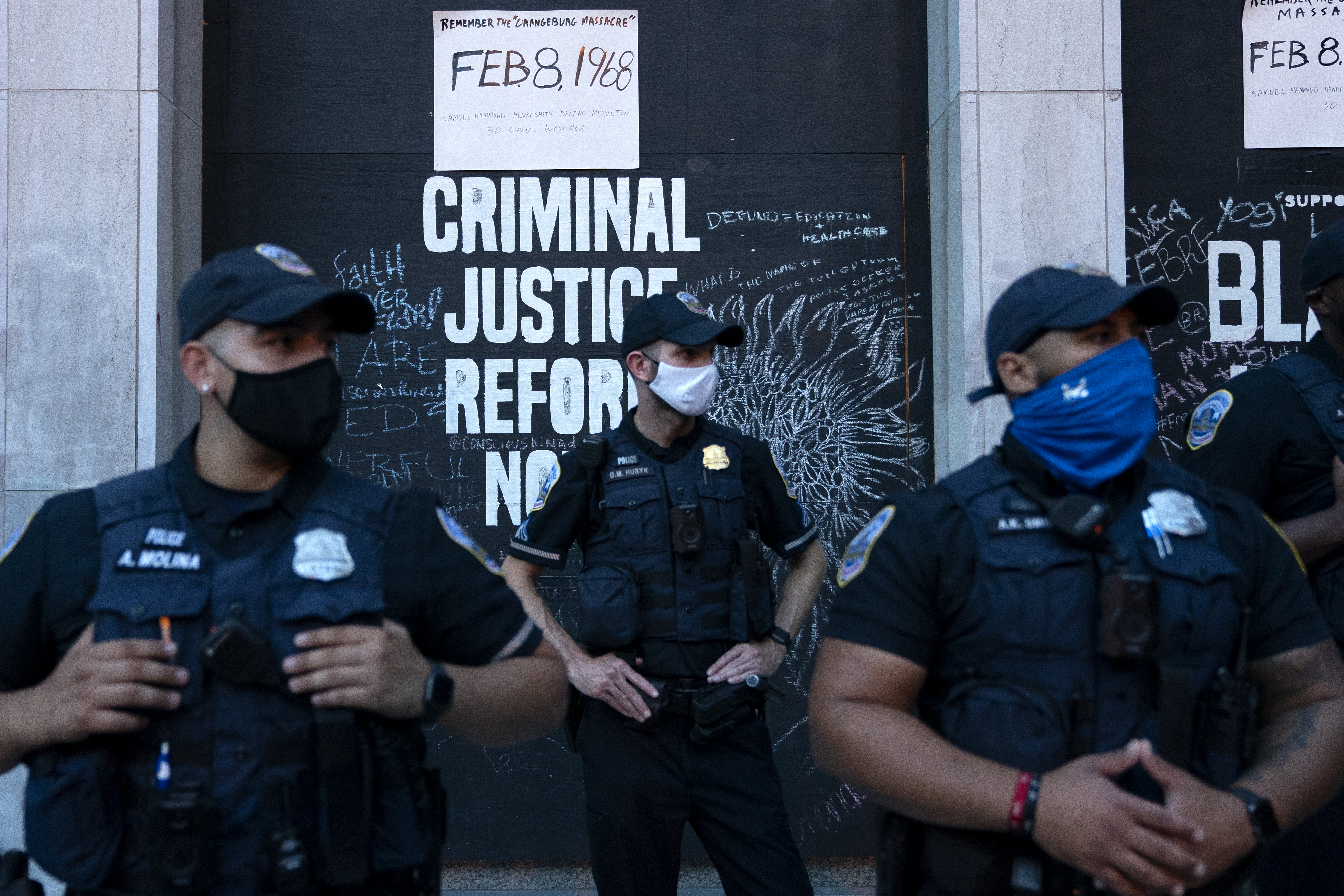 Police officers wearing protective masks stand in front of a criminal justice reform sign during the Republican National Convention in Washington, D.C., on Aug. 27, 2020. (Stefani Reynolds—Bloomberg/Getty Images)