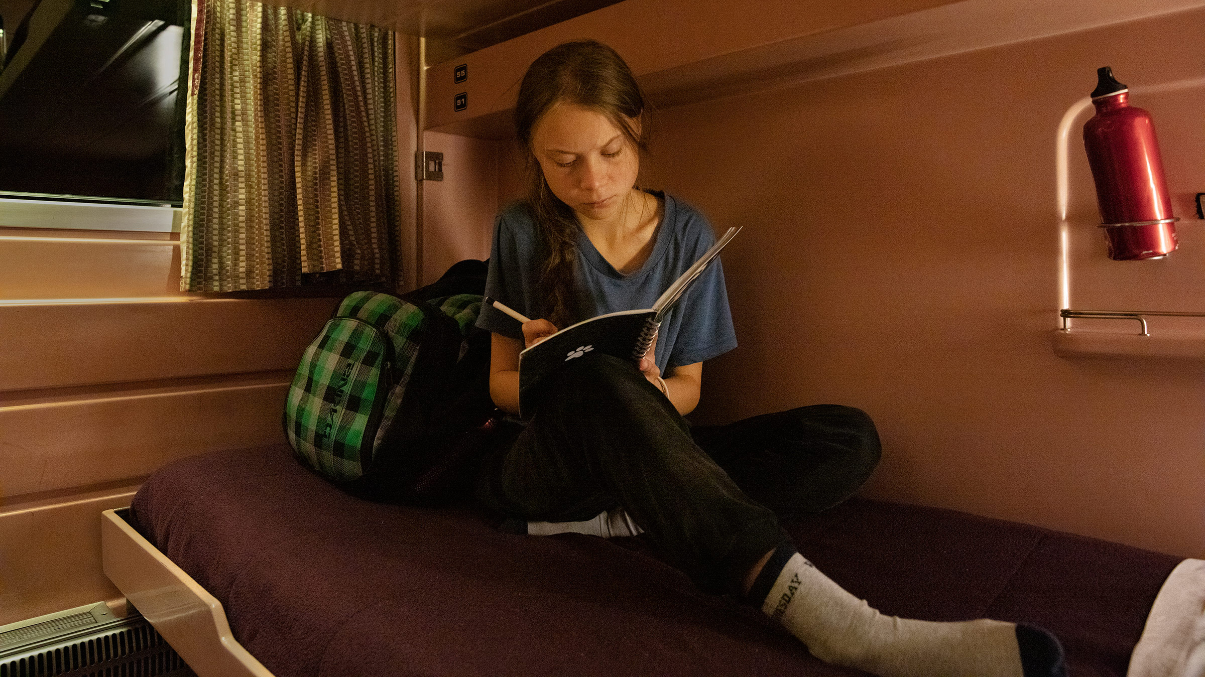 Greta Thunberg writes in her journal on the train as she travels from Lisbon to Madrid for a U.N. climate conference on Dec. 5, 2019. (Evgenia Arbugaeva for TIME)