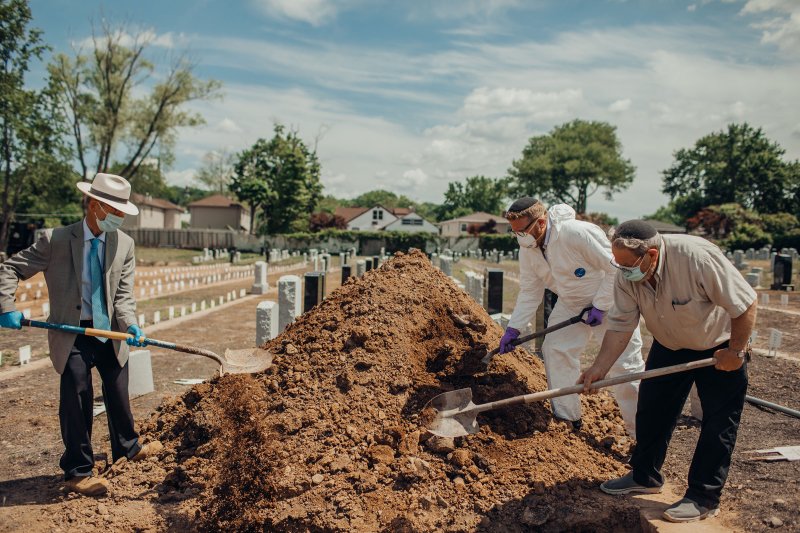 Rabbi Shmuel Plafker, an Orthodox chaplain, left, and volunteers place the last shovelfuls of dirt upon Ellen Torron’s grave.