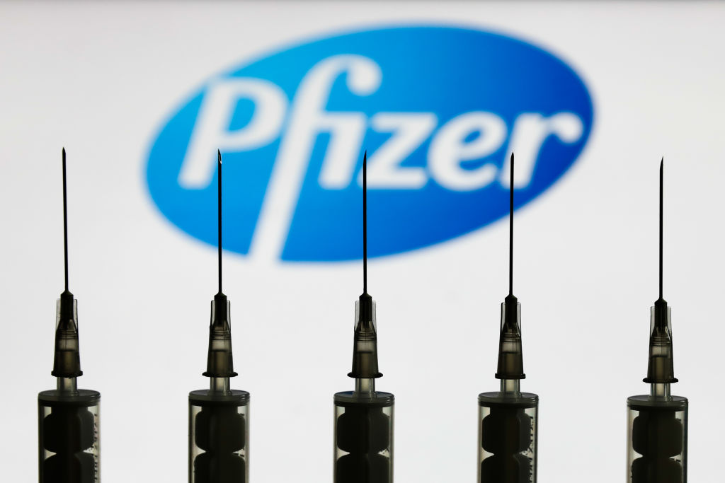 Medical syringes are seen with Pfizer company logo displayed on a screen in the background in this illustration photo taken in Poland on October 12, 2020. (Jakub Porzycki—NurPhoto via Getty Images)