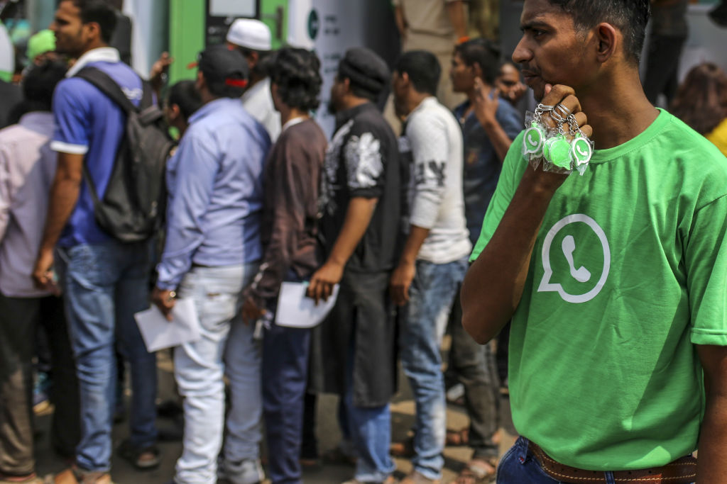 A WhatsApp ambassador holds branded key chains as spectators stand in line during a roadshow for WhatsApp's messaging service and Reliance Jio Infocomm Ltd.'s wireless network in Pune, India, on Thursday, Oct. 25, 2018. (Dhiraj Singh/Bloomberg via Getty Images)