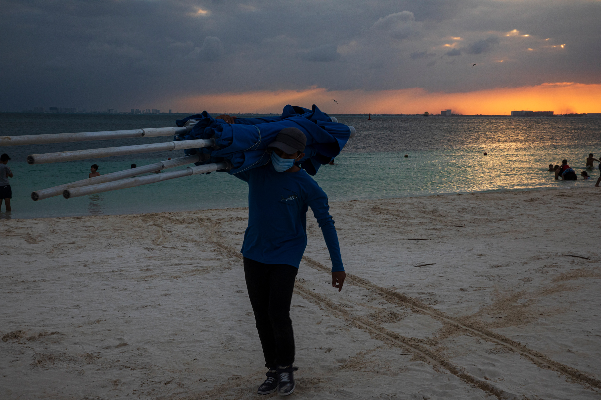 A worker collects beach umbrellas at the end of the day at Isla Mujeres, Quintana Roo, on Dec. 2.
