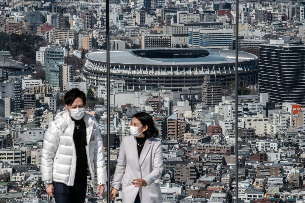 A couple wearing face masks walks away after viewing the New National Stadium, the main stadium for the Tokyo 2020 Olympics, as they visit the Shibuya Sky observation deck on March 24, 2020 in Tokyo, Japan. (Carl Court/Getty Images)