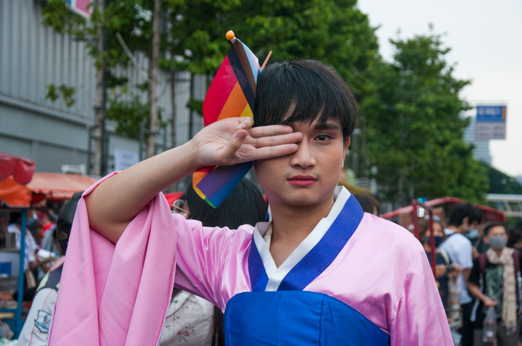 A protester wearing a Korean traditional dress makes three