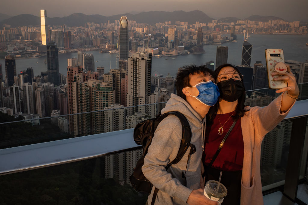 A couple wearing protective masks take a selfie at an observation deck at Victoria Peak on December 2, 2020 in Hong Kong, China. (Anthony Kwan/Getty Images)