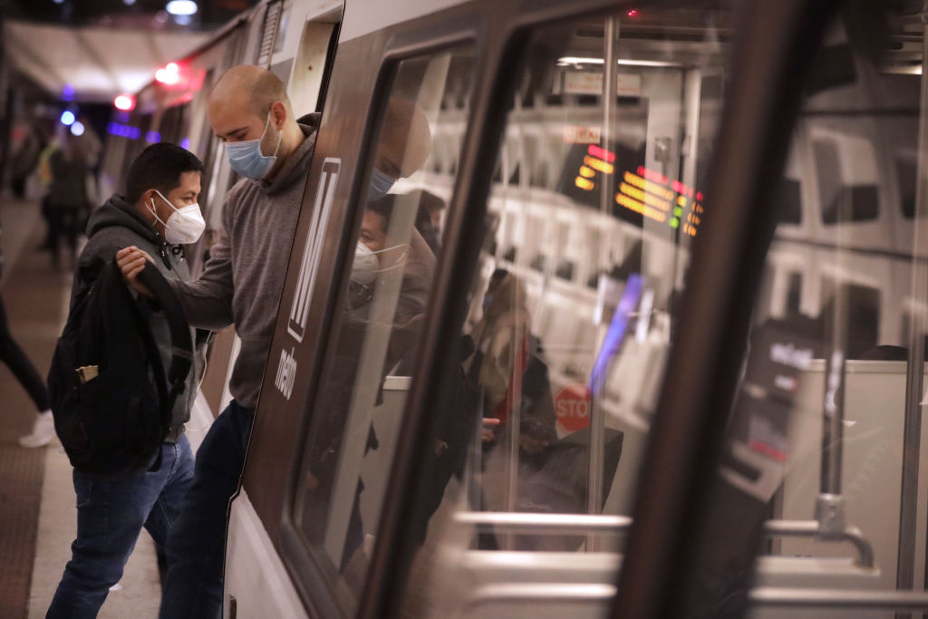 Wearing masks to reduce the risk posed by the coronavirus pandemic, commuters step in and out of a Metro train car at the Metro Center station December 02, 2020 in Washington, DC. (Photo by Chip Somodevilla/Getty Images)